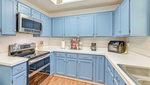 A kitchen with blue cabinets, a microwave, an oven, and a sink. - Pet-Friendly Family Home 3 Mi to Lake Lewisville (Lewisville)