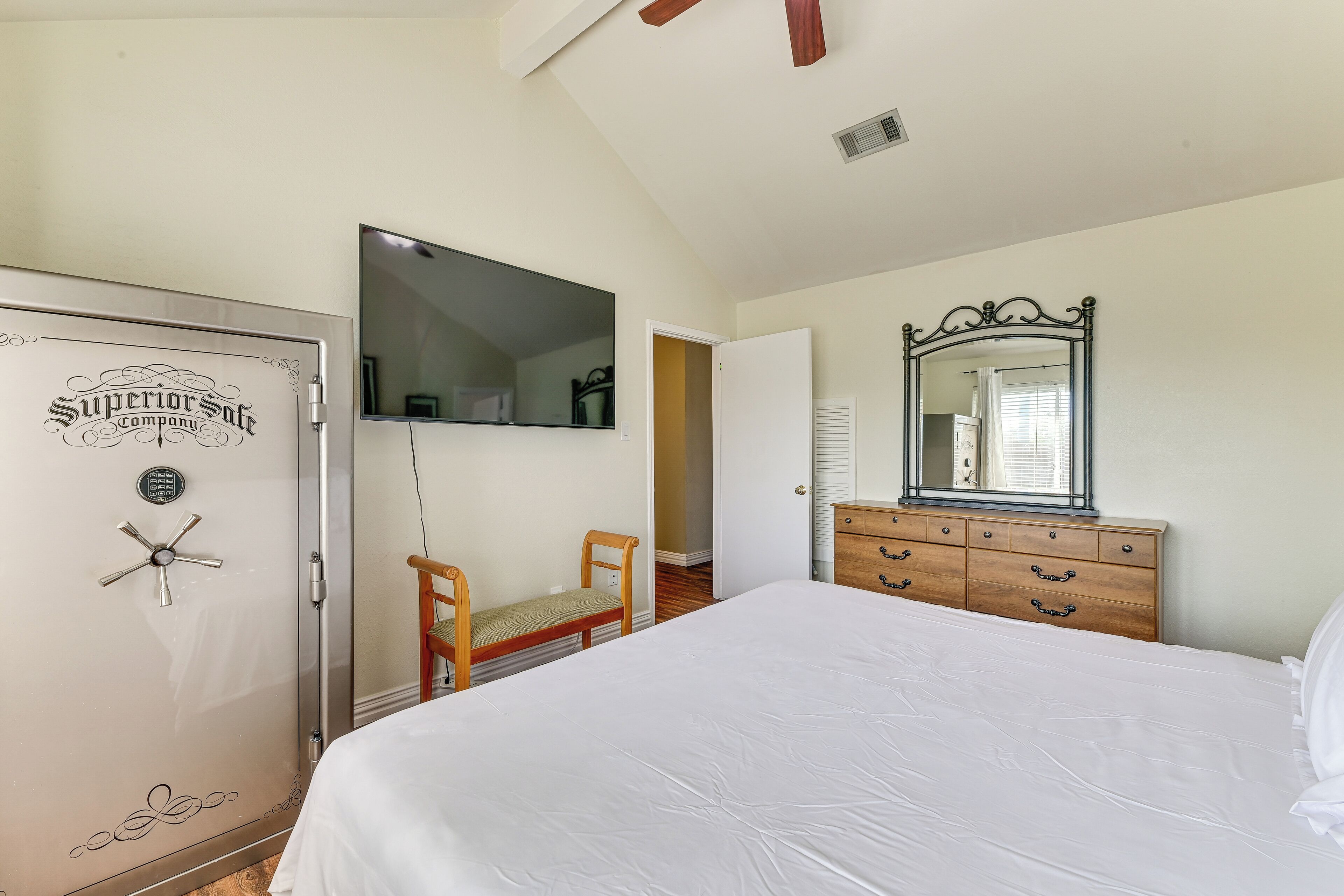 A bedroom with a bed, a dresser, a chair, a wardrobe, and a mirror.