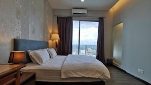 A hotel room with a bed, a desk, a lamp, a view of the city, and a large window. - Mykey Silverscape B-39-06 Melaka City (Melaka)
