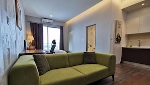 A living room with a sofa, a wooden coffee table, a desk with a chair, and a view of the outside through a window. - Mykey Silverscape B-39-06 Melaka City (Melaka)
