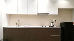 A modern kitchen with white cabinets, a stainless steel range hood, a black refrigerator, and a wooden countertop. - Mykey Silverscape B-39-06 Melaka City (Melaka)