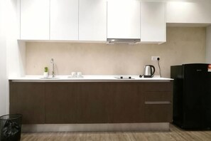 Une cuisine moderne avec des meubles blancs, une hotte en acier inoxydable, un réfrigérateur noir et un plan de travail en bois.