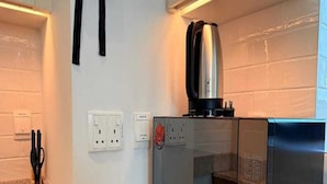 A compact kitchen with a built-in microwave, a coffee maker, and a refrigerator. - Premium Studio In Jvc Bazr (Dubai)