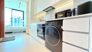 A modern kitchen with a built-in oven, microwave, and washing machine. - Premium Studio In Jvc Bazr (Dubai)