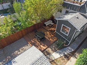 A deck with outdoor furniture, a small shed, and a wooden fence. - The Sunny | 2 Suites | 10 Pax | Pet Friendly Stay! (Calgary)