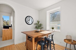 Un coin repas avec une table en bois, des chaises noires, une horloge et une plante en pot.