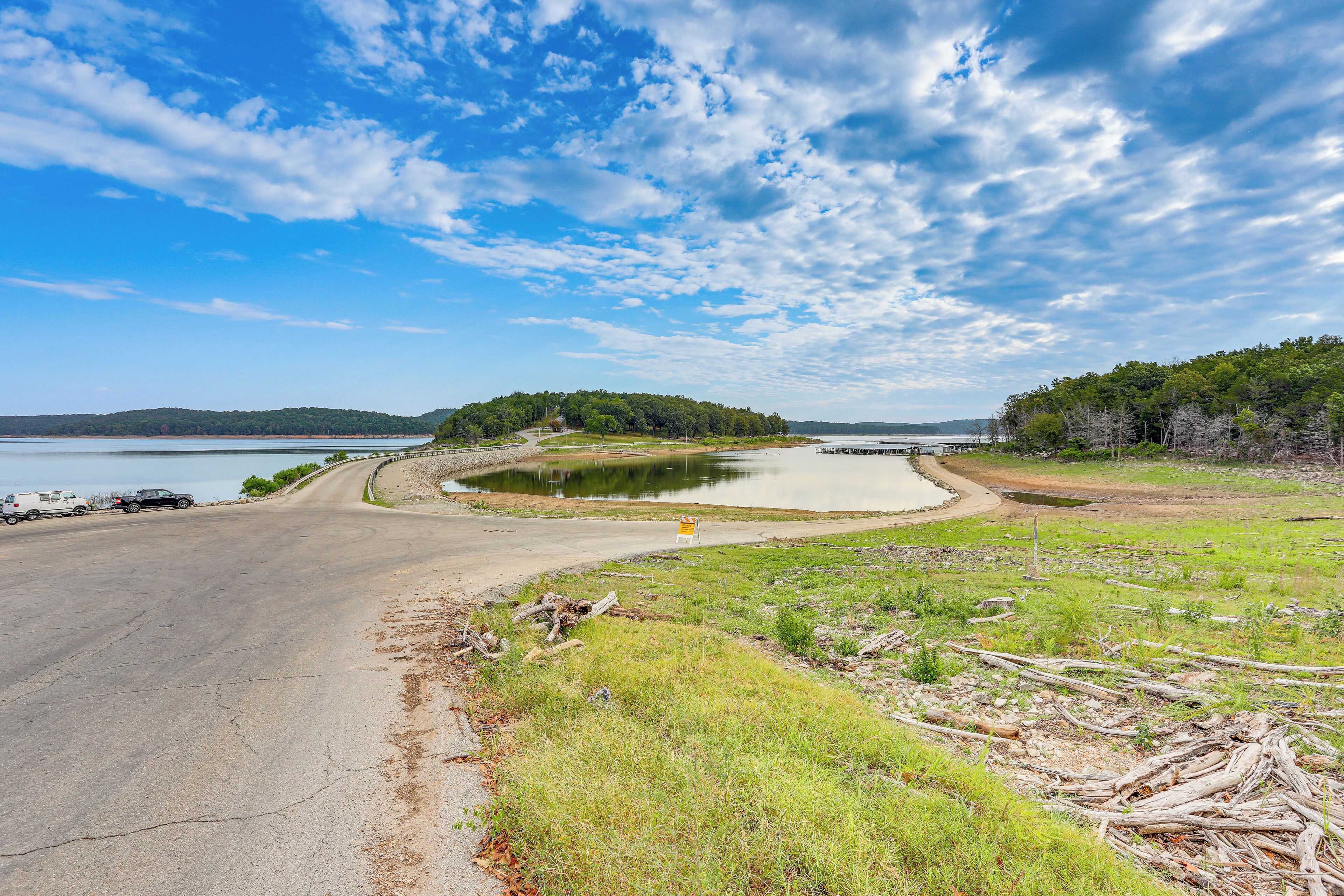 A road curving around a body of water with a small island in the distance.