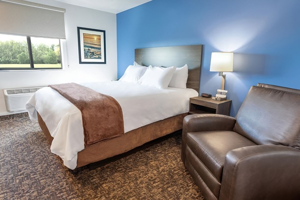 Unwind in crisp linens with cozy chair and warm lighting.