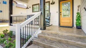 A wooden front door with a glass panel, a white staircase with a metal railing, and a small potted plant beside the door. - 1 Mi to Dtwn Brenham! 'The Bell & Bloom Cottage' (Brenham)