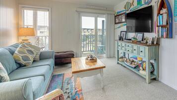A living room with a sofa, a coffee table, a TV, and a bookshelf.