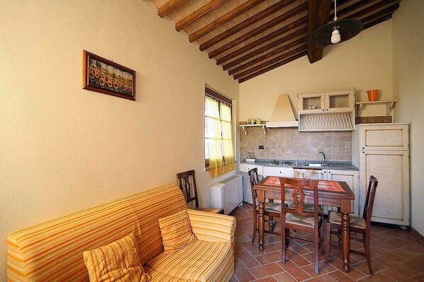 Una cocina acogedora con una mesa y sillas, una ventana con cortinas y techo de madera.