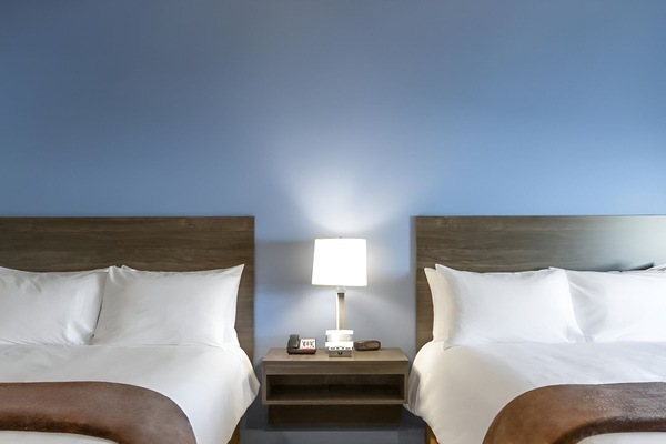 Drift off between two plush beds with soft bedside glow.
