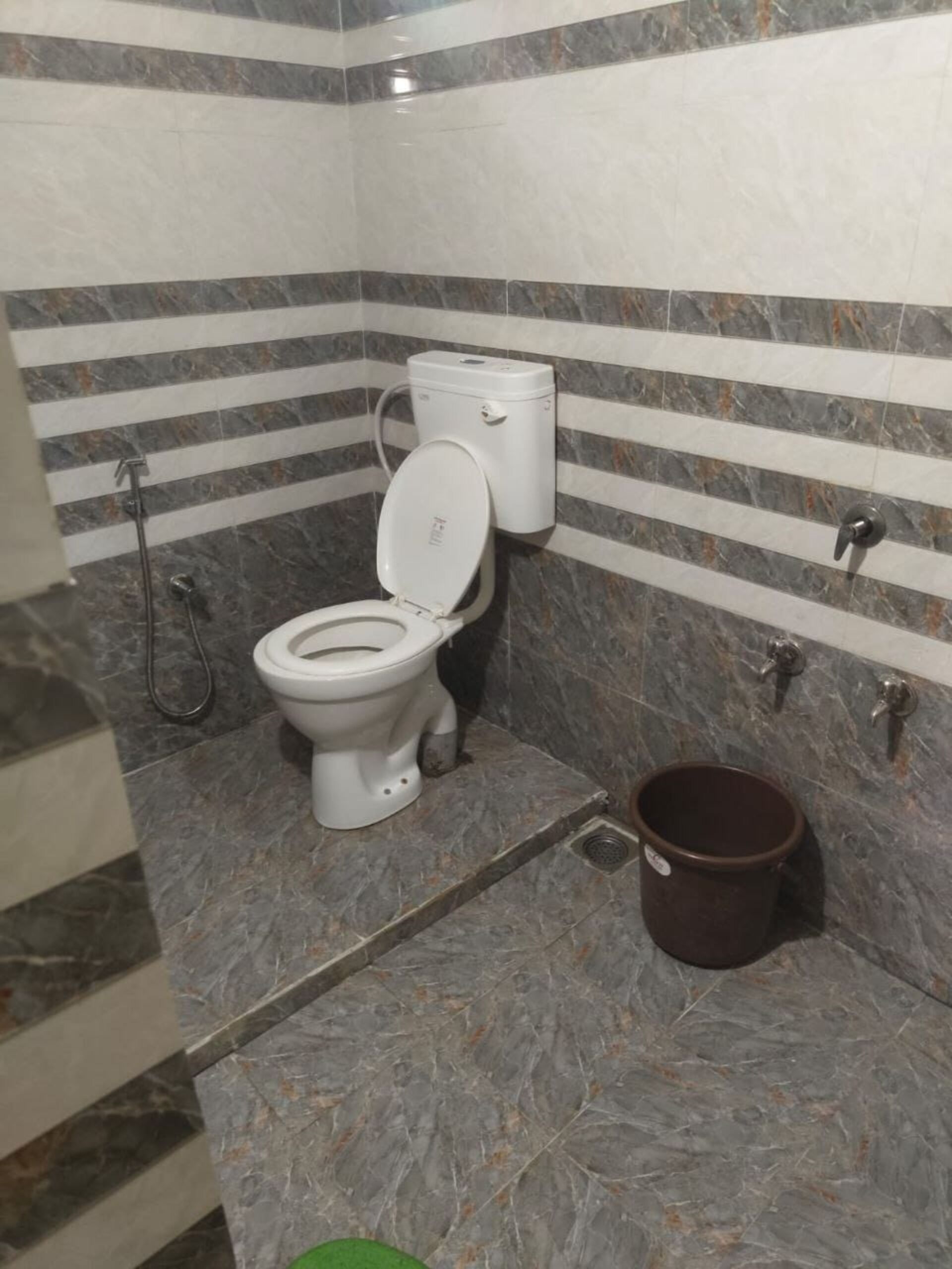 A bathroom with a toilet, a bidet, and a bucket.