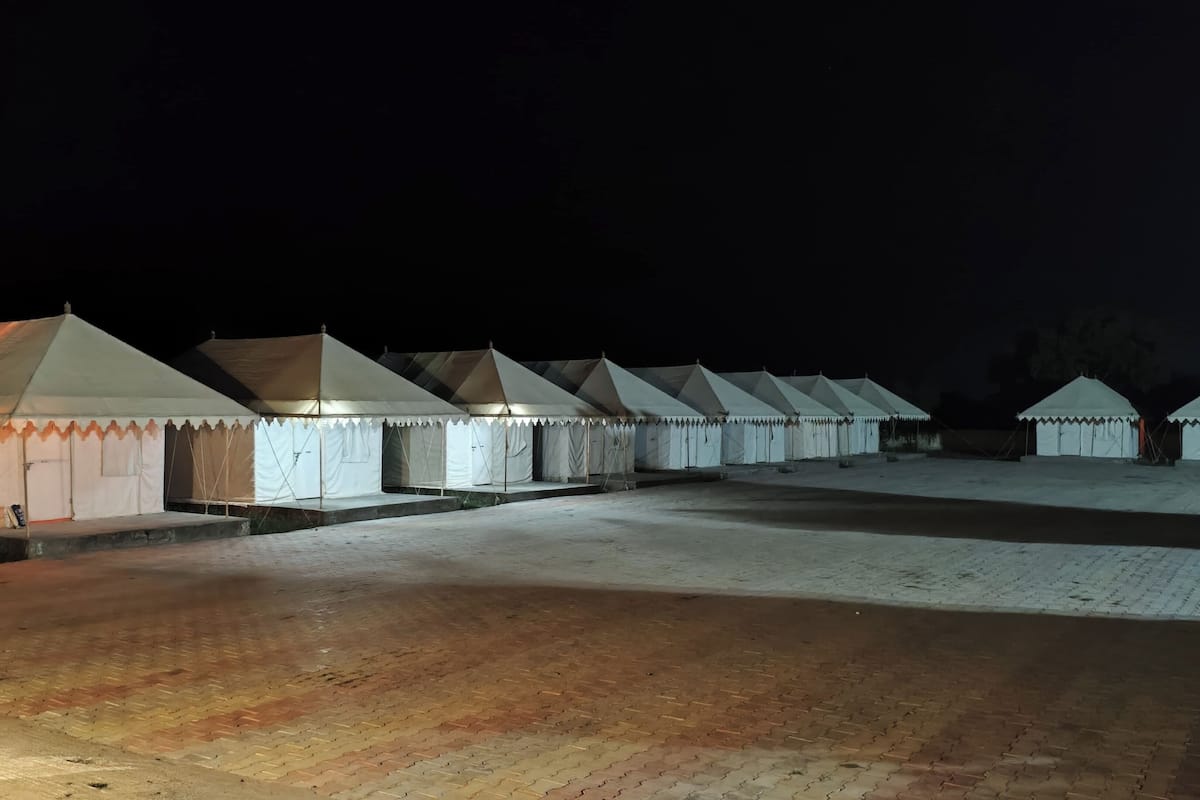 A row of white tents with a flat roof, arranged in a line on a paved ground.