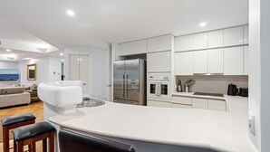 A modern kitchen with white cabinetry, a stainless steel refrigerator, and a built-in oven.