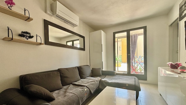 A modern living room with a sofa, a coffee table, a mirror, and a balcony with a view. - LOVELY ALL-INCLUSIVE GROUND-FLOOR 2-BEDROOM APARTMENT WITH TWO TVS AND WIFI NETFLIX (Le Barcarès)