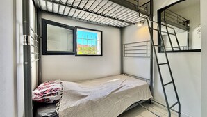 A compact room with a bunk bed, a window with a view, a ladder, and a small rug. - LOVELY ALL-INCLUSIVE GROUND-FLOOR 2-BEDROOM APARTMENT WITH TWO TVS AND WIFI NETFLIX (Le Barcarès)