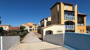 Une rue résidentielle bordée de maisons dotées de balcons, avec un ciel dégagé.