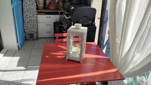A small dining area with a red table, a candle in a lantern, and a blue door. - LOVELY ALL-INCLUSIVE GROUND-FLOOR 2-BEDROOM APARTMENT WITH TWO TVS AND WIFI NETFLIX (Le Barcarès)