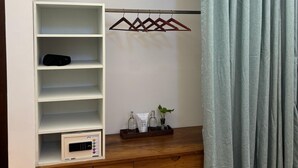 A room with a built-in wardrobe, a microwave, a tray with toiletries, and a hanging clothes rack. - Baron's antiquarian villa (Kochi)