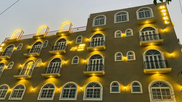 Ein Hotelgebäude mit mehreren Balkonen, großen Bogenfenstern und einer auffälligen 'HOTEL'-Beschilderung an der Fassade.