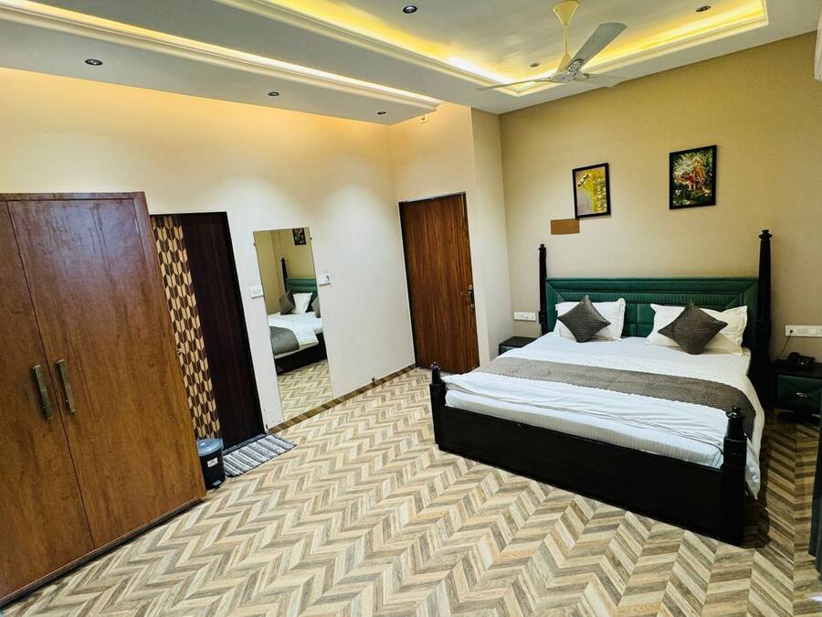 A hotel room with a large bed, a wardrobe, a mirror, and a ceiling fan.