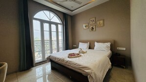 Ein Hotelzimmer mit einem großen Bett, einem Fenster mit Aussicht und einem kleinen Nachttisch.