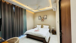Ein Hotelzimmer mit Bett, Schreibtisch, Stuhl, Deckenventilator und Wandklimaanlage.