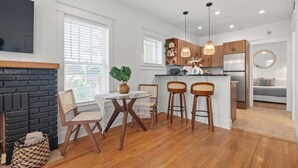 A modern kitchen with wooden cabinets, a central island with bar stools, a built-in oven, and a large refrigerator.