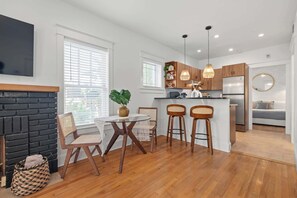 Une cuisine moderne avec des meubles en bois, un îlot central doté de tabourets, un four encastré et un grand réfrigérateur.