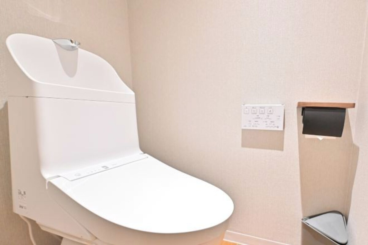 Een modern toilet met een wandbediend spoelmechanisme en bedieningspaneel.