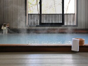 Un onsen japonais traditionnel, avec un banc en bois et un seau en bois.