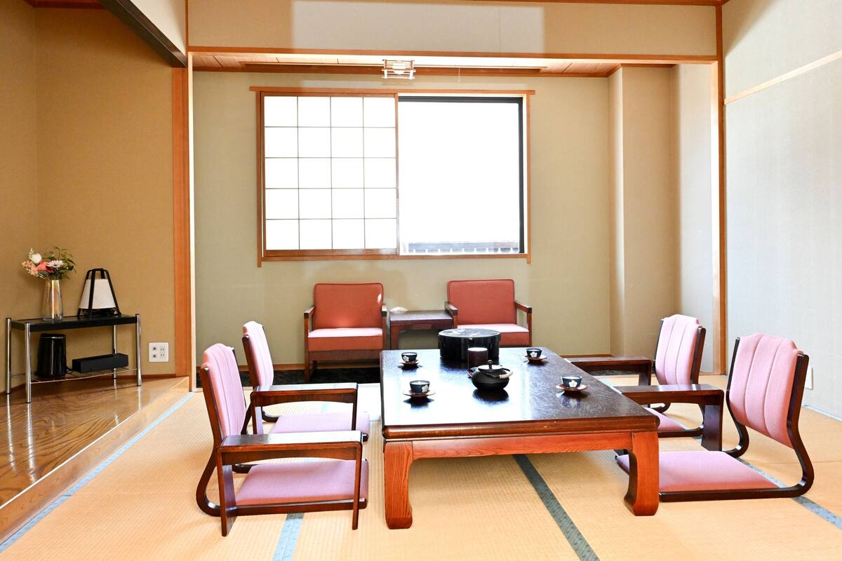 Una sala de reuniones al estilo tradicional japonés, con suelo de tatami, una mesa baja y sillas de madera.