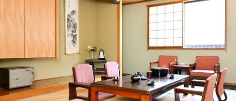 Una sala de reuniones tradicional japonesa con suelo de tatami, una mesa baja y sillas de madera.