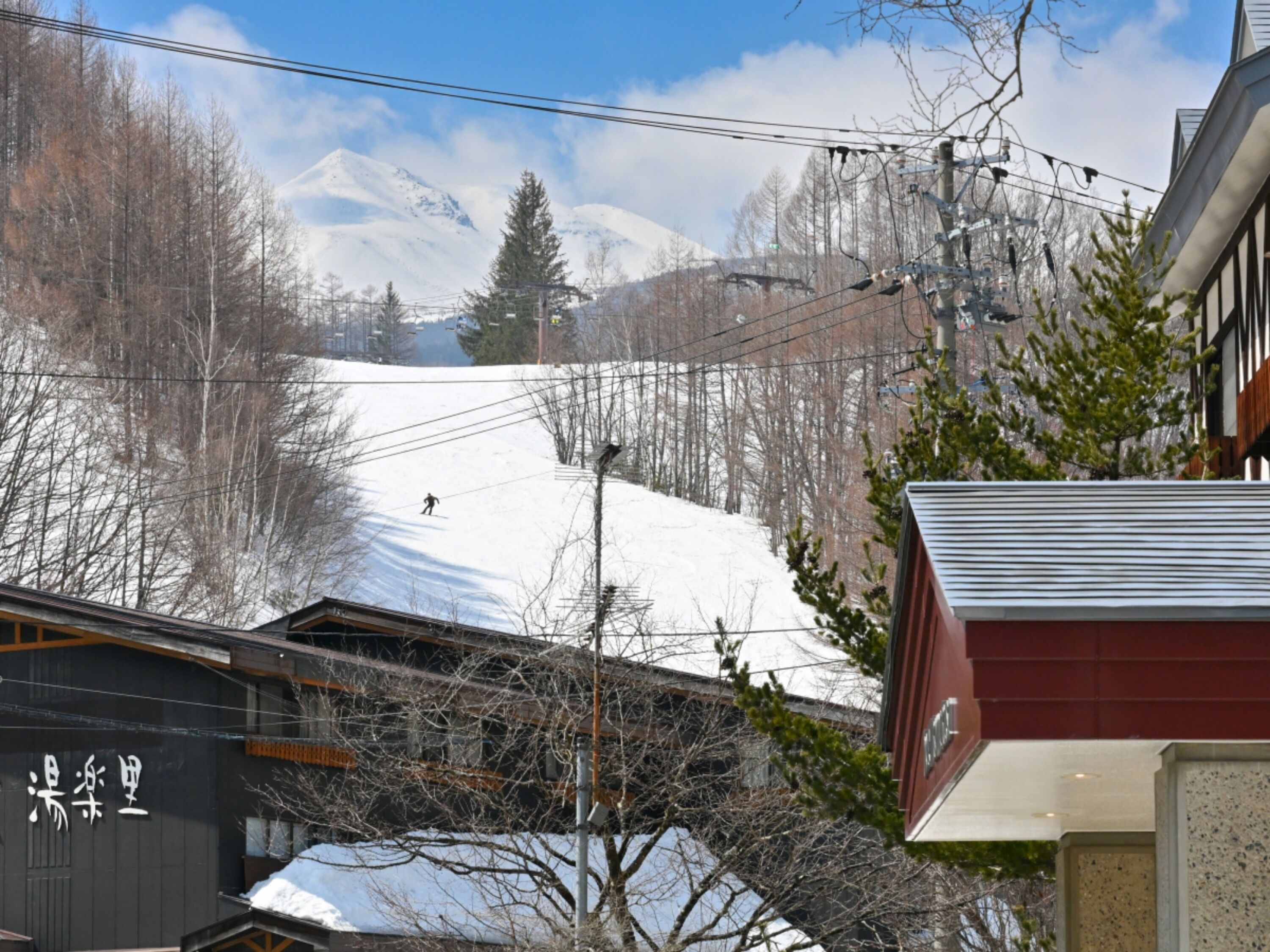 A ski resort with a snow-covered slope, buildings, and a clear sky.
