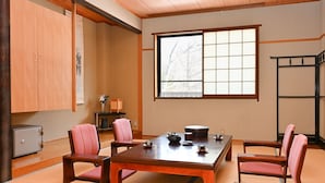 A traditional Japanese-style room with tatami flooring, a low wooden table, and matching chairs. - Komakusa Hotel (Matsumoto)