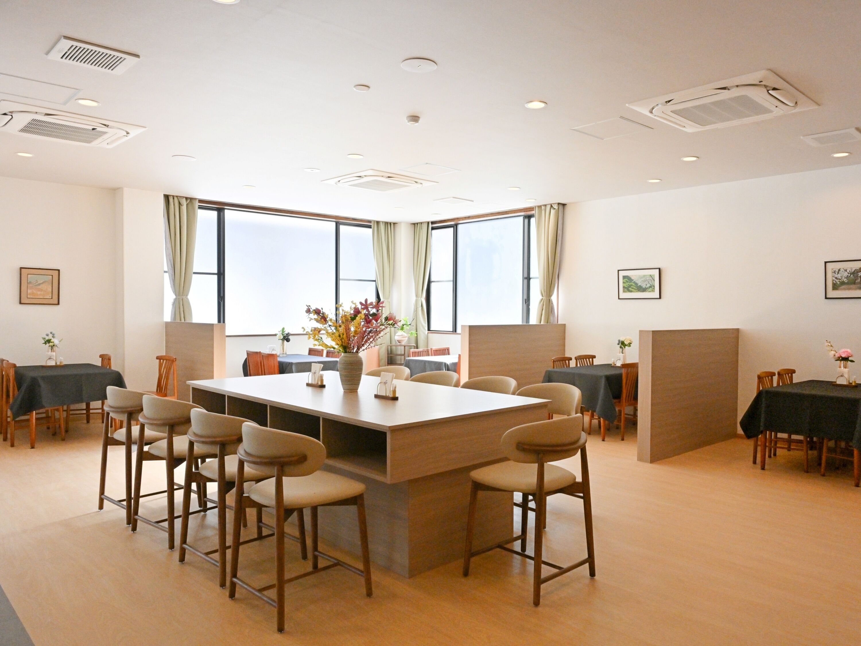 A conference room with a large table, multiple chairs, and large windows.