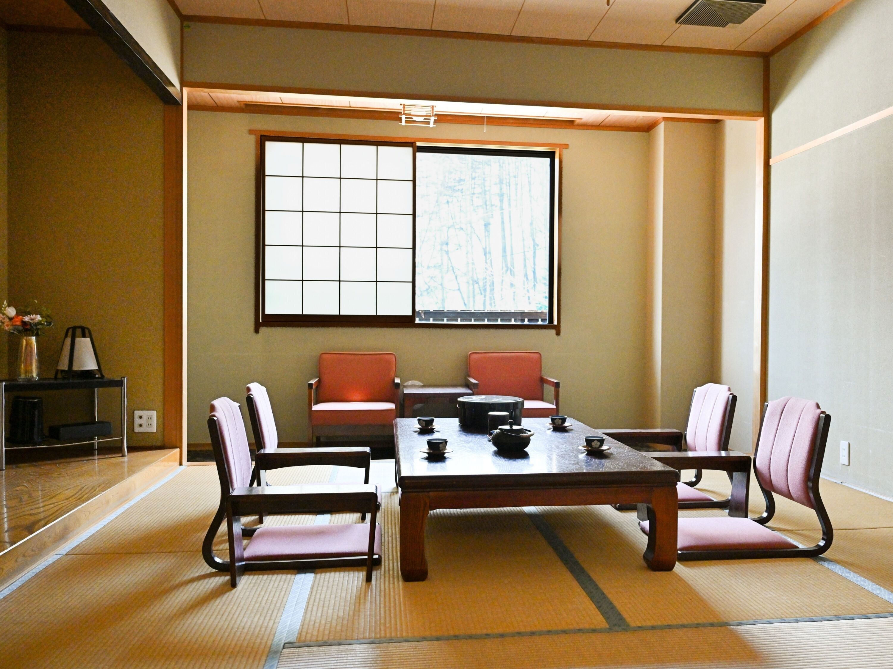 Una habitación tradicional japonesa con suelo de tatami, una mesa baja y cuatro sillas.