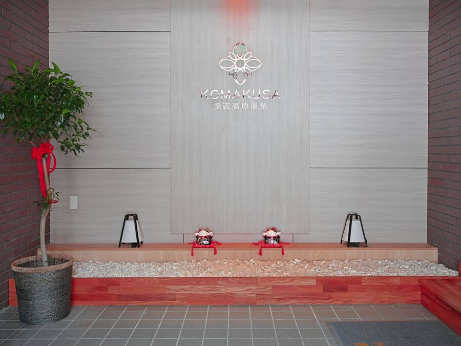 Zona de recepción con diseño moderno, que incluye un logotipo, un mostrador de recepción y un área de estar con dos sillones.