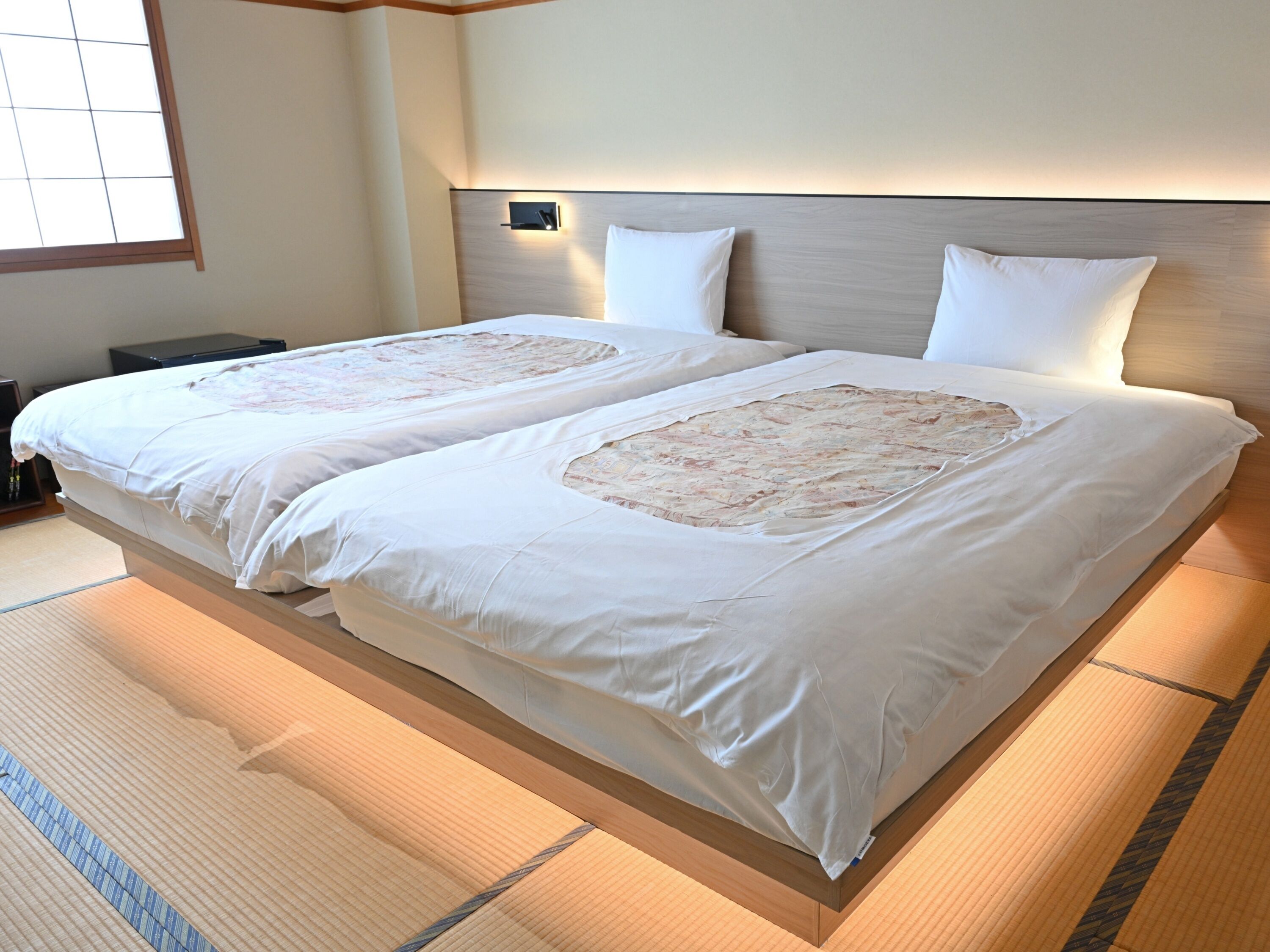 A double bed with a wooden headboard, white bedding, and a small bedside table.