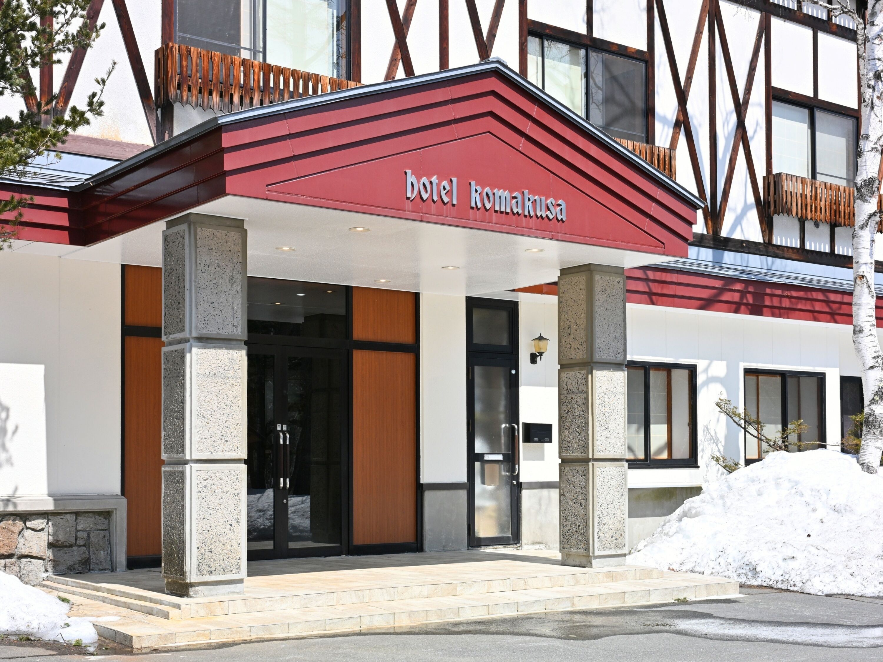 A hotel entrance with a red awning and stone pillars.
