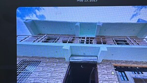 Un bâtiment à la façade en briques, doté d’une grande porte ouverte et d’un escalier métallique menant à un étage supérieur.