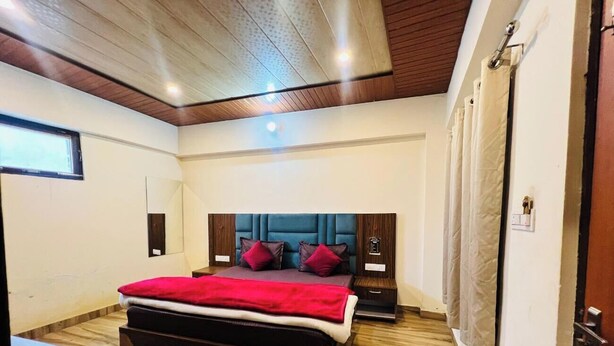 Une chambre à coucher comprenant un lit, un plancher en bois, une tête de lit, des tables de chevet, un bureau et une fenêtre.