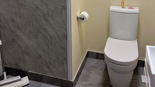 A bathroom with a toilet, a marble wall, and a tiled floor. - Chapel Barn (Bedford)