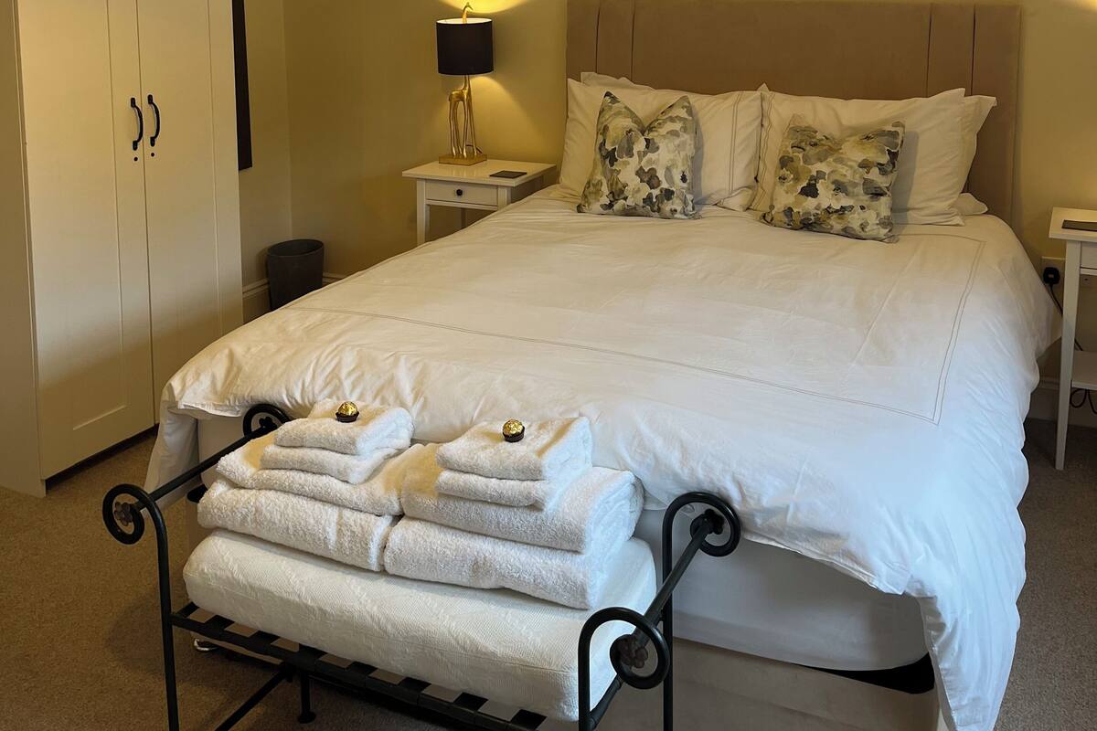 Un dormitorio ordenado con cama, mesitas de noche, un armario y una lámpara colgante.