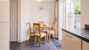 A compact kitchen with a dining table, chairs, and a clock on the wall.