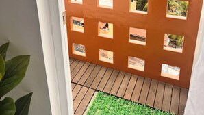 A balcony with a wooden floor and a view of a cityscape through a brown partition with square cutouts. - Meteor Garden (Cebu City)