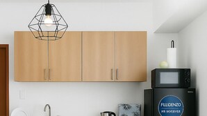 A modern kitchen with wooden cabinets, a black refrigerator, a kettle, and a coffee maker. - Meteor Garden (Cebu City)