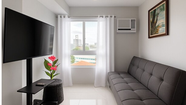 A modern living room with a flat-screen TV, grey sofa, and a window with white curtains. - Meteor Garden (Cebu City)