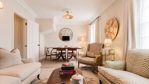 Una sala de estar con sofá, sillón, mesa de centro y un comedor con mesa y sillas.